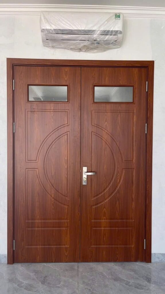 Bộ cửa composite hai cánh vân gỗ nâu, ô kính phía trên và họa tiết huỳnh tại Hai Bà Trưng