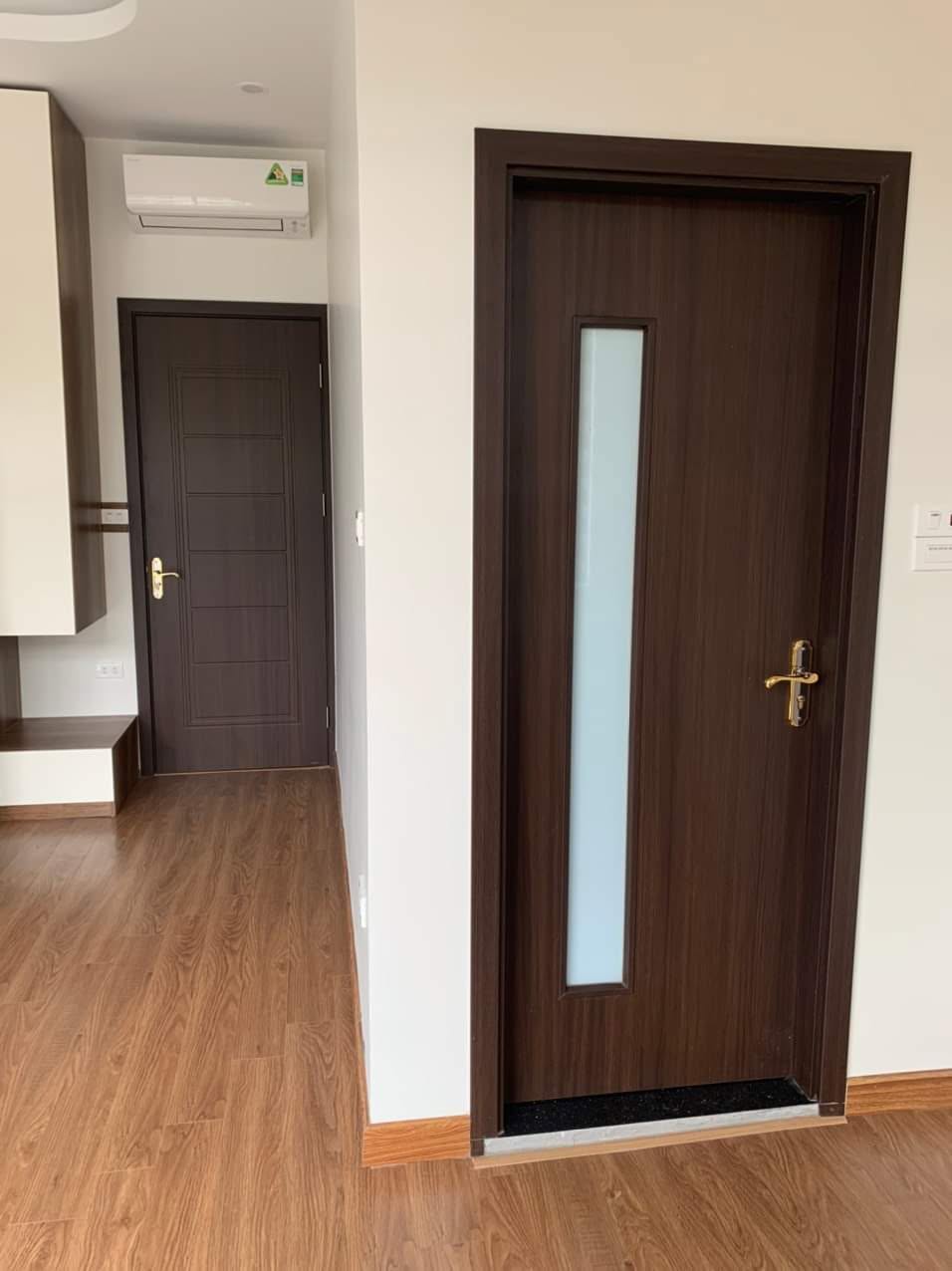 Cửa composite ô kính đứng vân gỗ nâu phối với sàn gỗ và nội thất tại Tây Hồ
