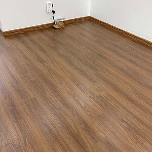 Mặt sàn Hobi H682 sau hoàn thiện trong phòng, kết hợp cùng tường trắng và phào chân tường màu gỗ